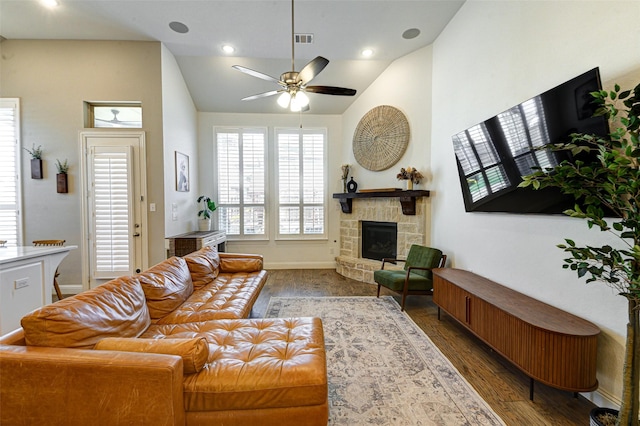 living area with lofted ceiling, a stone fireplace, wood finished floors, and visible vents