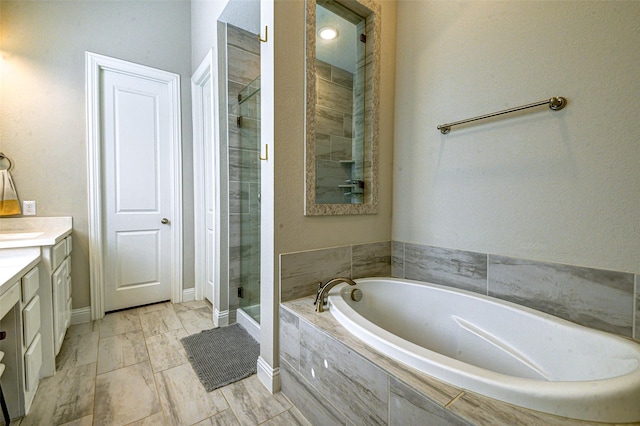 bathroom featuring a bath, a shower stall, vanity, and baseboards