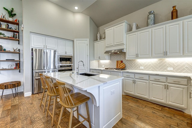 kitchen with decorative backsplash, stainless steel appliances, white cabinetry, a sink, and exhaust hood