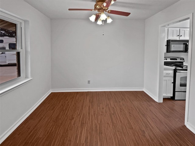 interior space featuring baseboards, white cabinets, stainless steel electric range oven, dark wood-style flooring, and black microwave