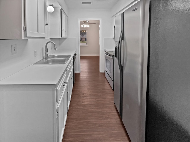 kitchen featuring dark wood-style floors, stainless steel appliances, light countertops, white cabinetry, and a sink