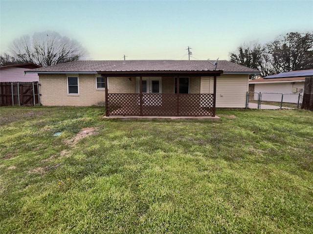 rear view of property with a patio, a fenced backyard, a gate, a yard, and brick siding