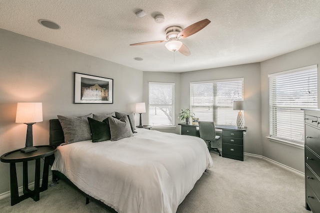 bedroom featuring light carpet, ceiling fan, a textured ceiling, and baseboards