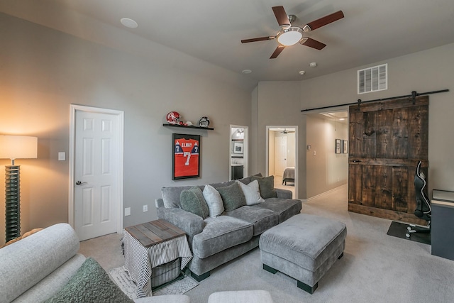 living area featuring a ceiling fan, carpet, visible vents, and a barn door