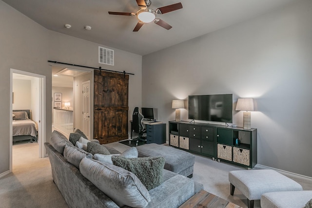 living area with a barn door, carpet flooring, visible vents, and a ceiling fan