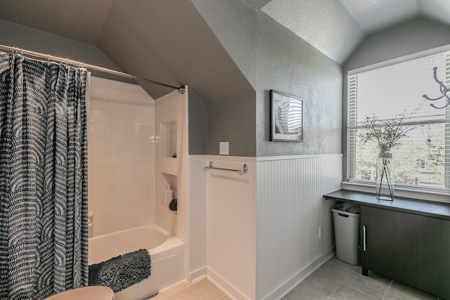 full bathroom featuring shower / bath combo, lofted ceiling, a wainscoted wall, tile patterned floors, and a textured ceiling