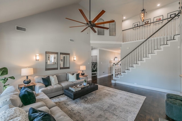 living area with washer / dryer, visible vents, baseboards, dark wood-style floors, and stairway