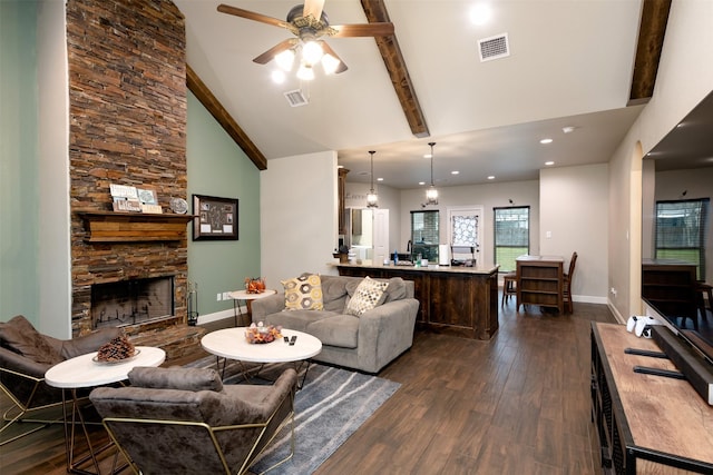 living area with high vaulted ceiling, visible vents, dark wood finished floors, and a stone fireplace