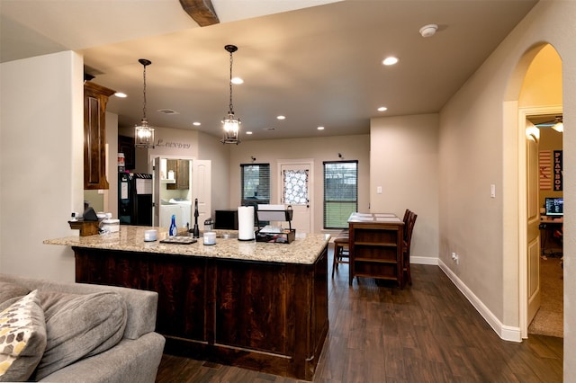 kitchen with baseboards, dark wood finished floors, a peninsula, washer and dryer, and recessed lighting