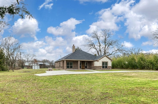 rear view of house featuring a storage shed, a patio, a chimney, an outbuilding, and a yard