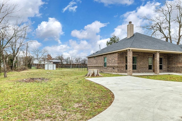 view of yard featuring driveway, an outdoor structure, fence, and a shed