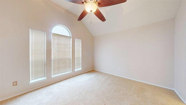 empty room featuring lofted ceiling, ceiling fan, baseboards, and light colored carpet