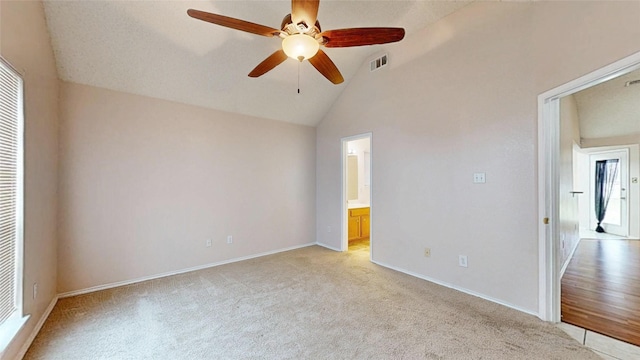 unfurnished room with vaulted ceiling, light carpet, visible vents, and baseboards