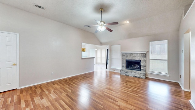 unfurnished living room featuring ceiling fan, visible vents, wood finished floors, and a stone fireplace