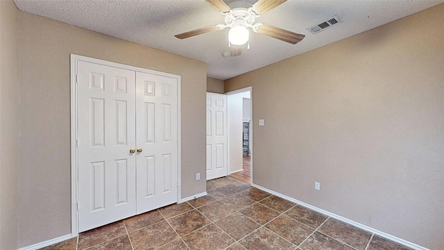 unfurnished bedroom featuring baseboards, visible vents, ceiling fan, a textured ceiling, and a closet