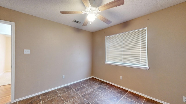 unfurnished room featuring a ceiling fan, visible vents, a textured ceiling, and baseboards