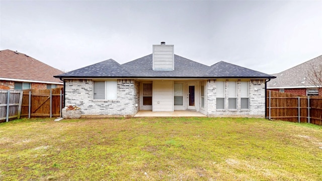 back of house featuring brick siding, a yard, a chimney, a patio area, and a fenced backyard