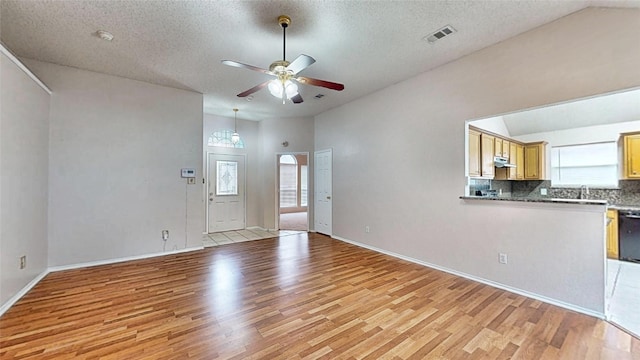 unfurnished living room featuring lofted ceiling, a wealth of natural light, light wood-type flooring, and visible vents