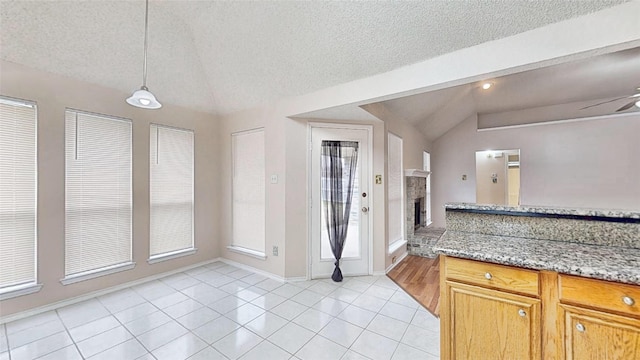 interior space with lofted ceiling, light tile patterned floors, a fireplace, and hanging light fixtures