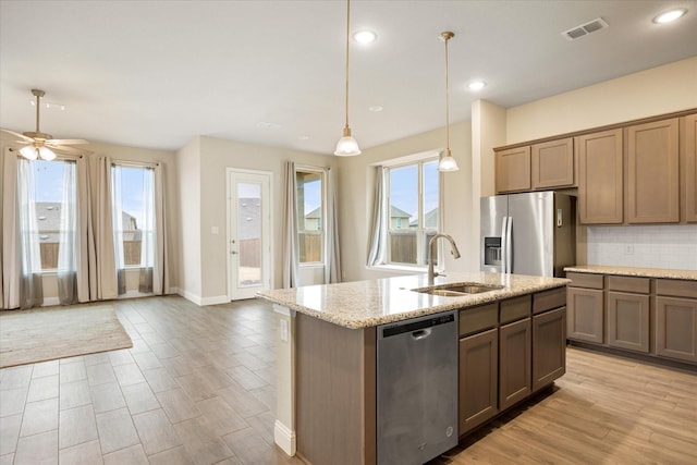 kitchen featuring tasteful backsplash, visible vents, stainless steel appliances, pendant lighting, and a sink