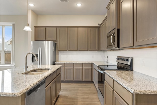 kitchen with stainless steel appliances, a sink, visible vents, light wood-type flooring, and decorative backsplash