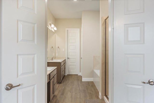 bathroom with vanity, baseboards, wood finished floors, and a shower with shower door