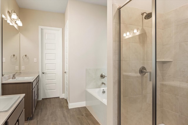 bathroom featuring a stall shower, two vanities, a sink, and wood finished floors