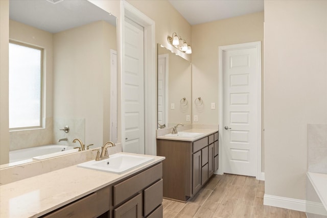 bathroom with a tub, vanity, baseboards, and wood finished floors