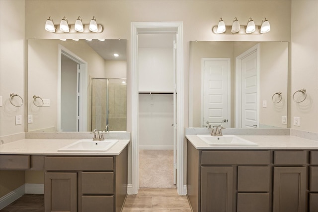 bathroom with a stall shower, two vanities, and a sink