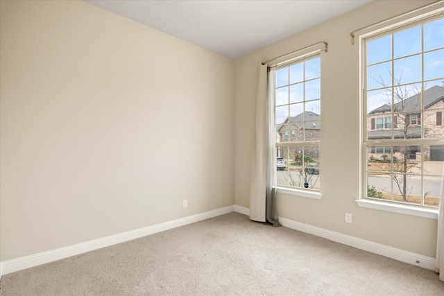 unfurnished room with light colored carpet and baseboards