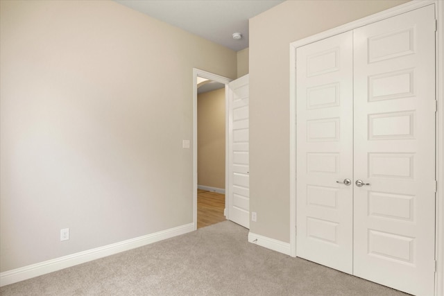 unfurnished bedroom featuring carpet floors, baseboards, and a closet