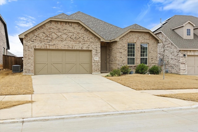 view of front of house with driveway, a shingled roof, an attached garage, cooling unit, and brick siding