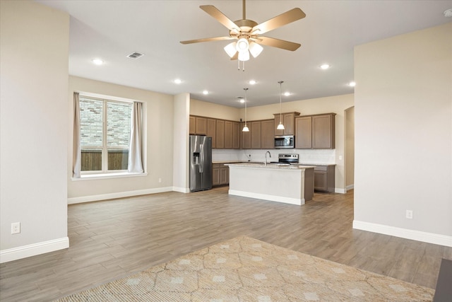 kitchen with light wood finished floors, visible vents, appliances with stainless steel finishes, open floor plan, and light countertops