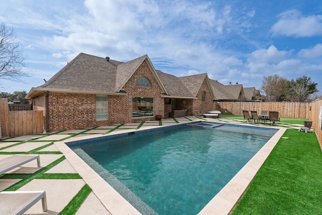 view of pool with a fenced backyard, a pool with connected hot tub, a lawn, and a patio