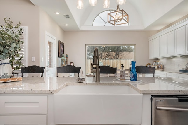 kitchen with a sink, visible vents, white cabinets, backsplash, and light stone countertops