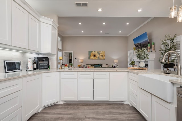 kitchen featuring crown molding, light wood finished floors, visible vents, white cabinets, and a sink