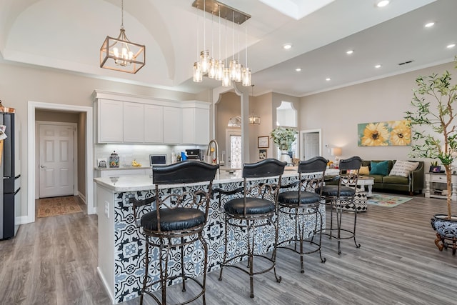 kitchen featuring backsplash, white cabinets, light wood-style flooring, and a kitchen bar