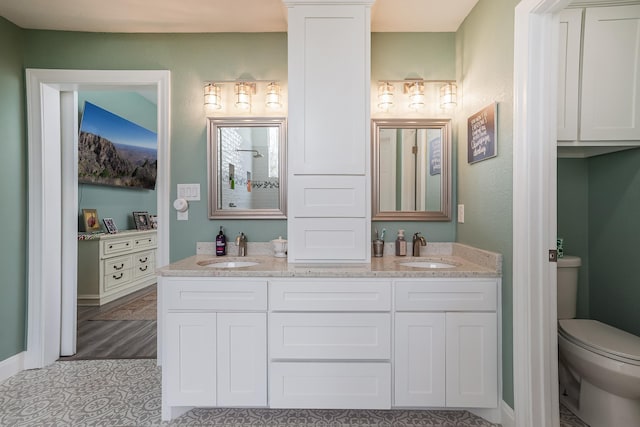 bathroom featuring toilet, double vanity, and a sink