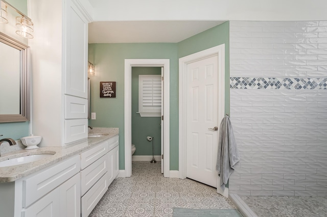 full bathroom featuring baseboards, a sink, a tile shower, and toilet