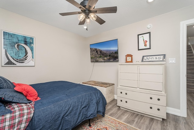 bedroom featuring ceiling fan, a textured ceiling, wood finished floors, and baseboards