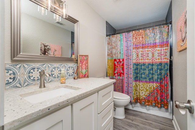 bathroom featuring shower / tub combo, visible vents, toilet, wood finished floors, and vanity