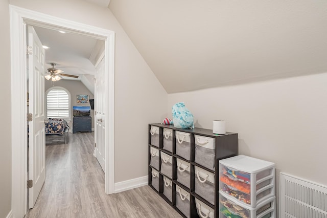 corridor with vaulted ceiling, light wood finished floors, and baseboards