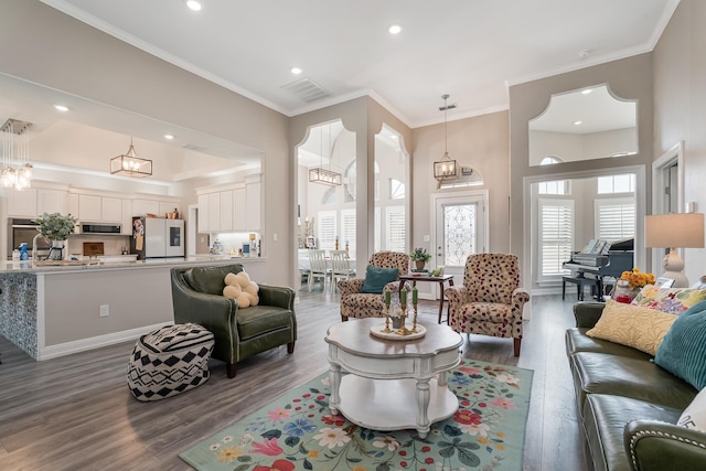 living area featuring ornamental molding, recessed lighting, visible vents, and wood finished floors