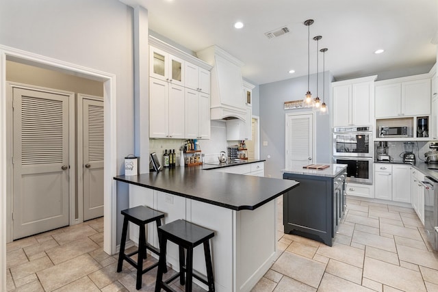 kitchen featuring tasteful backsplash, dark countertops, stainless steel appliances, visible vents, and a peninsula