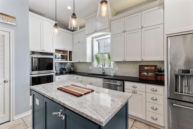 kitchen featuring a center island, light tile patterned floors, stainless steel appliances, tasteful backsplash, and a sink