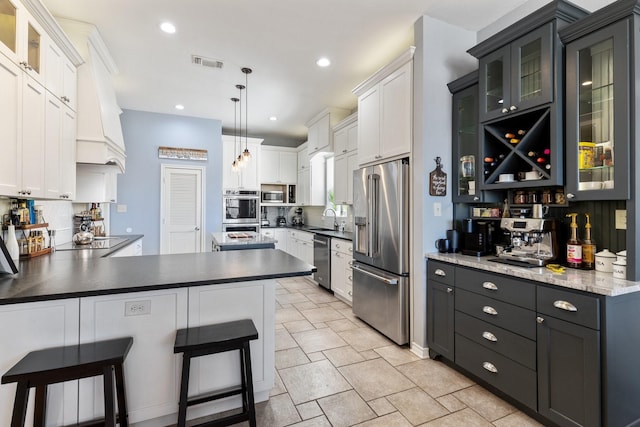 kitchen featuring recessed lighting, stainless steel appliances, a peninsula, a sink, and visible vents