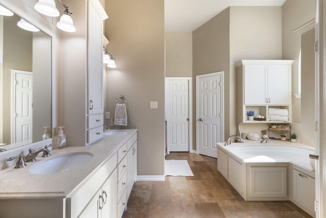 bathroom featuring double vanity, a garden tub, baseboards, and a sink