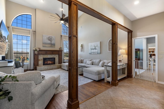 living room featuring ceiling fan, light tile patterned flooring, recessed lighting, a high ceiling, and a high end fireplace