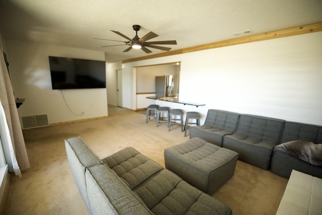 living room featuring baseboards, visible vents, a ceiling fan, and light colored carpet