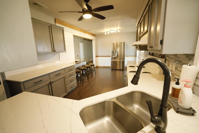 kitchen featuring under cabinet range hood, a ceiling fan, visible vents, stainless steel refrigerator with ice dispenser, and gray cabinets